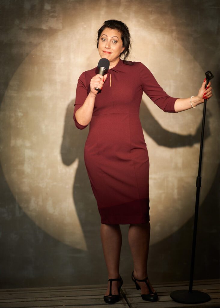 Stacy Pederson confidently speaking with a microphone in a studio setting.